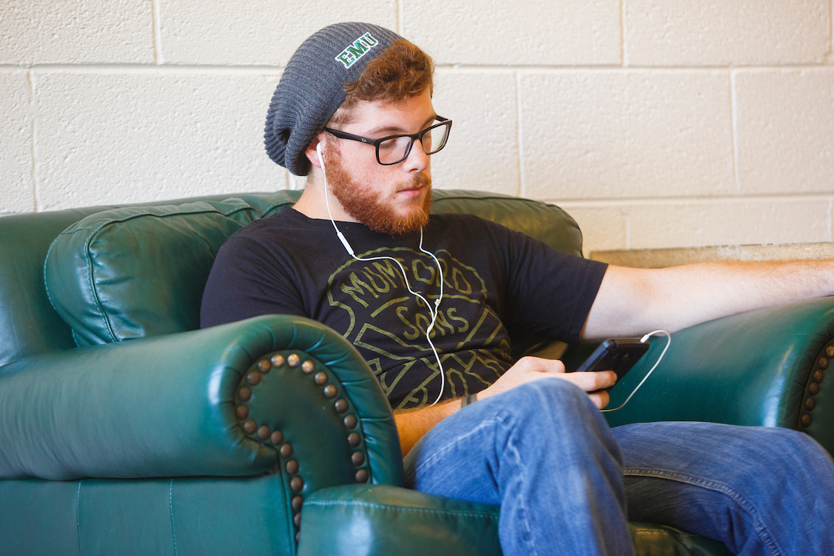Photo of a male student in EMU gear listening to music 