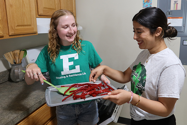 Two students baking together in a residence hall.
