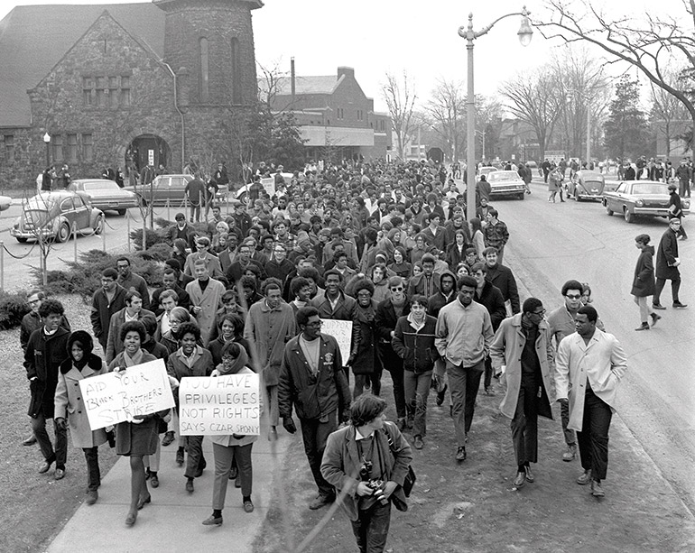 A black and white photograph of a group of students marching a protest