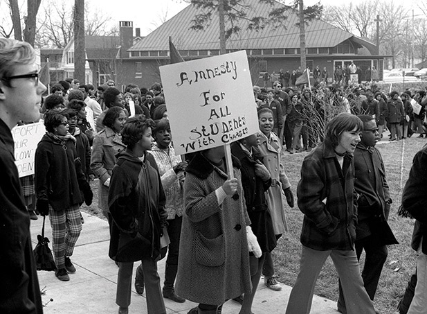 A black and white photograph of a group of protestors with signboards marching