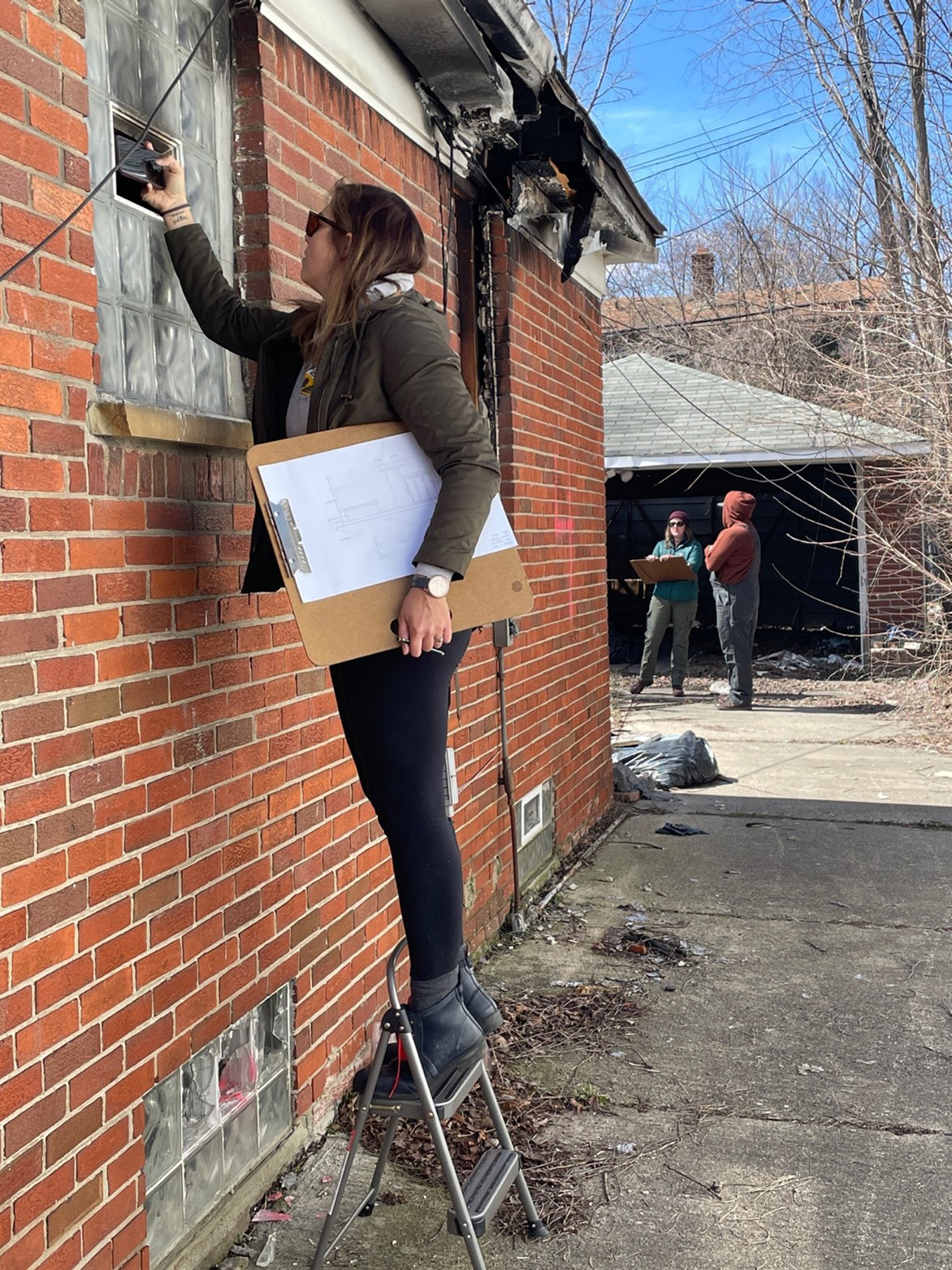 EMU Preservation students Jaclyn Panter, Brooke Boyst, and Taylor Williams record damage to the Malcom X House on Detroit’s east side with photographs and drawings, April 2, 2023 (Dan Bonenberger).