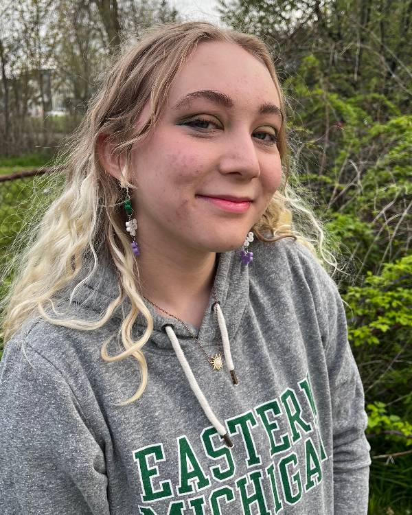 Smiling person with long blond hair outside