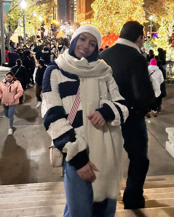 smiling person outdoors with hat and scarf