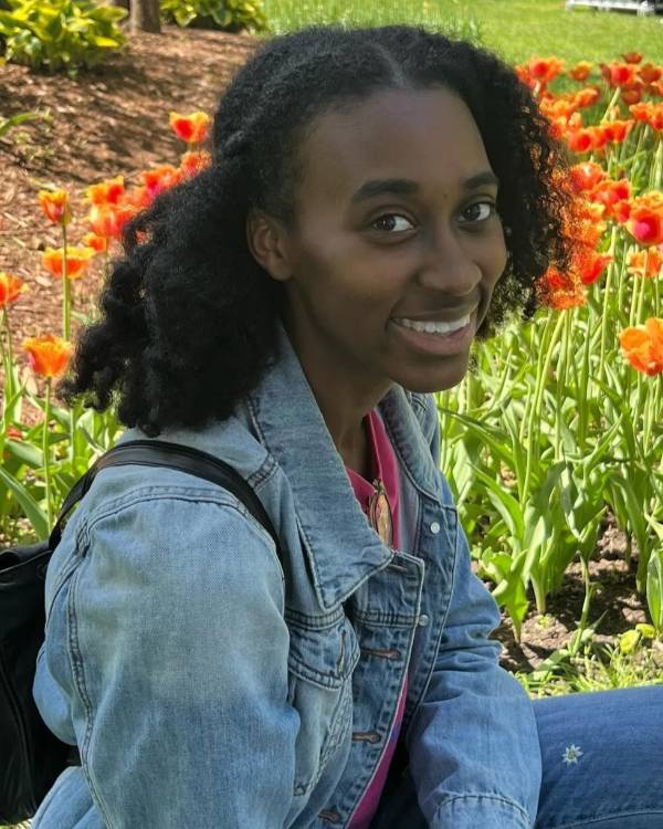 Smiling person outside near flowers