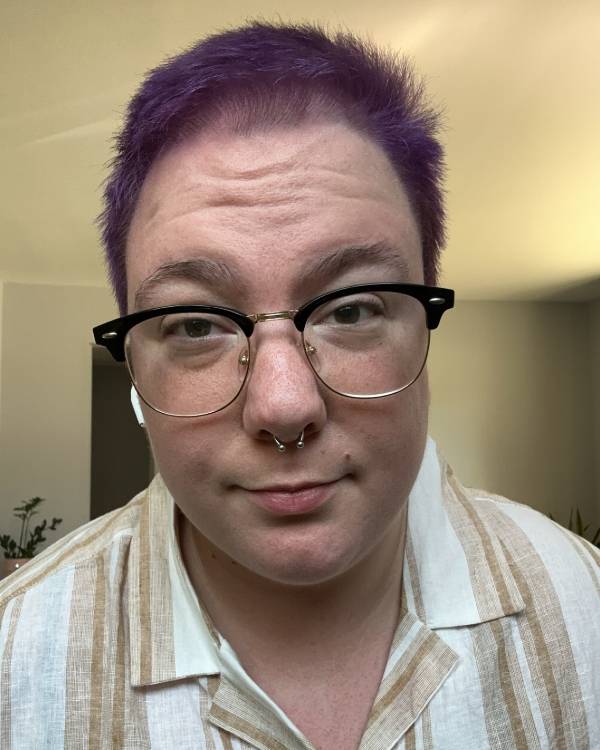 Smiling person with glasses and short hair