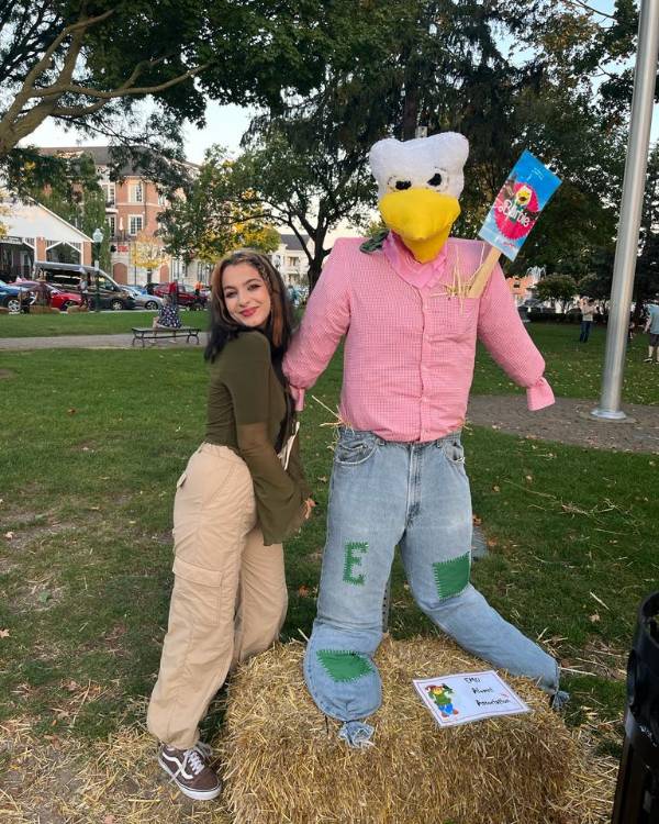 Smiling person posing with an EMU Eagle scarecrow