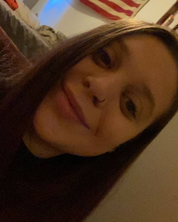 Smiling person indoors with dim lighting