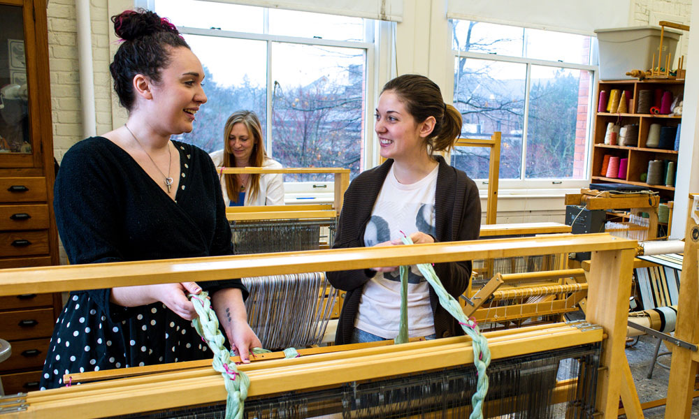 Two female students use the weaver.