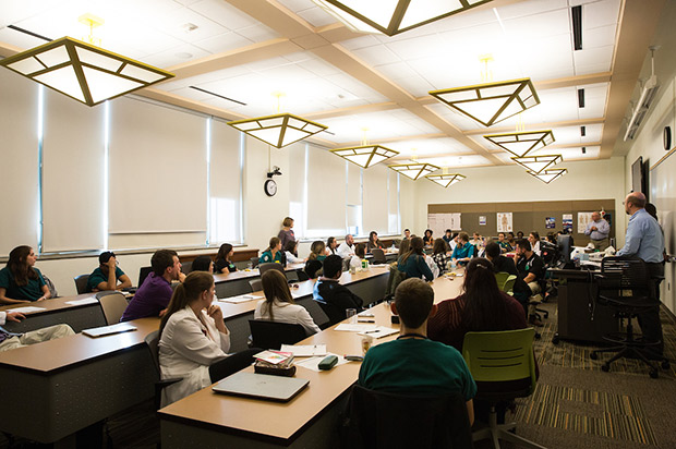 A photo shows a classroom of students listening to a lecture.