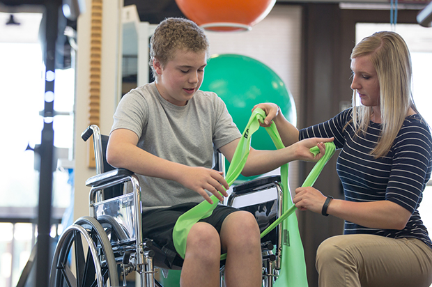 A student helps a patient in a wheelchair.