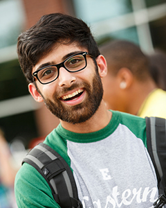 A male student with a beard and glasses smiles at the camera.