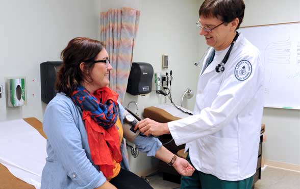 A male nurse takes a female patient's blood pressure.