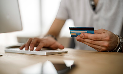 A person with a credit card in hand paying online