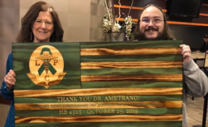 A photo of Irene Ametrano and Chris DeBoer holding a wooden plaque that reads, "Thank you Dr. Ametrano"! We can never communicate our gratitude for your tireless efforts. H.B. 4325 October 29, 2019