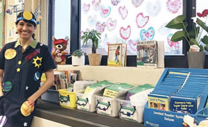 A photo of Brenda Gonzalez standing near story books available to her class
