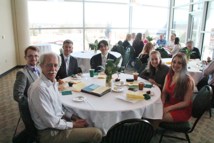 A group of people sits around atable at the Economics Department Annual Awards.