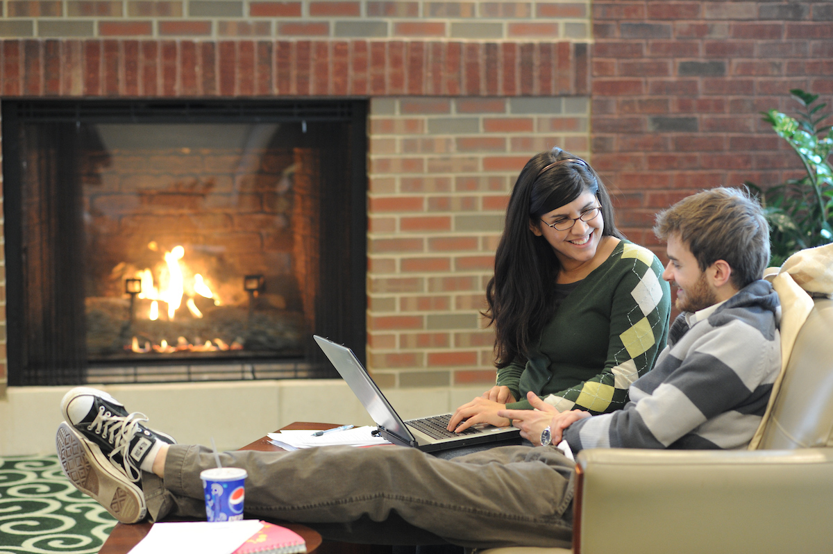 Two students reading by a fireplace