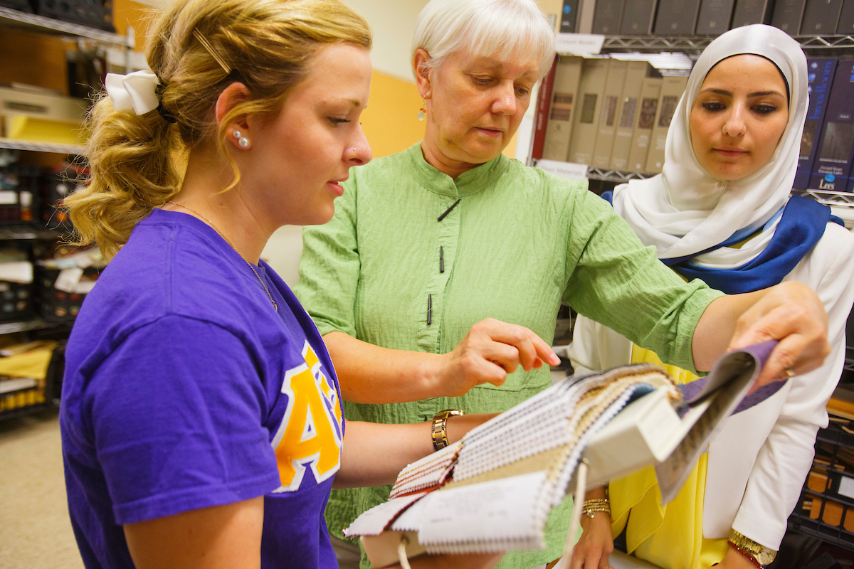 A female instructor showing two students something in a book