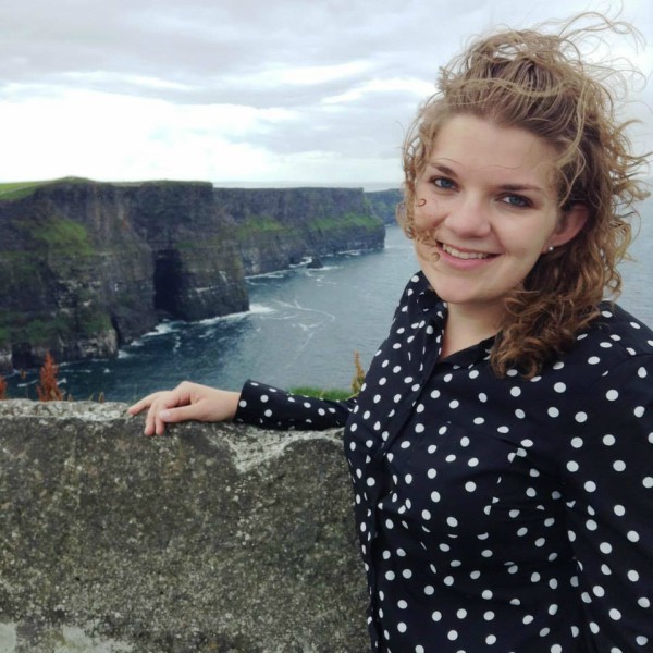 Young woman standing at the Cliffs of Moher and smiling into the camera
