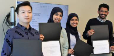 Students stand showing their certificates.