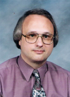 Dr. Wegner's headshot. He is wearing a tie and a purple dress shirt.