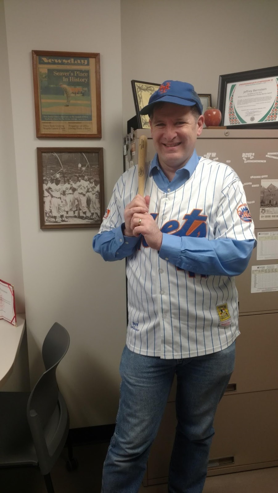 Image of Jeff Bernstein dressed in Met's gear and holding a baseball bat. 
