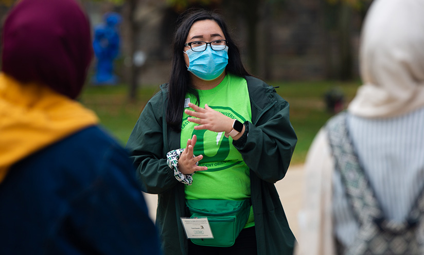 A photo of an EMU student giving a tour and wearing a mask.