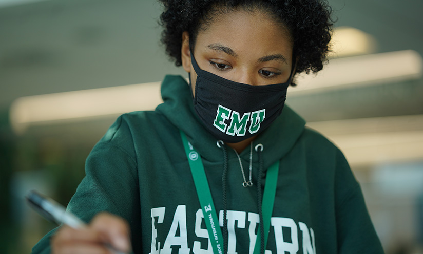 A photo of an EMU student studying and wearing a mask.