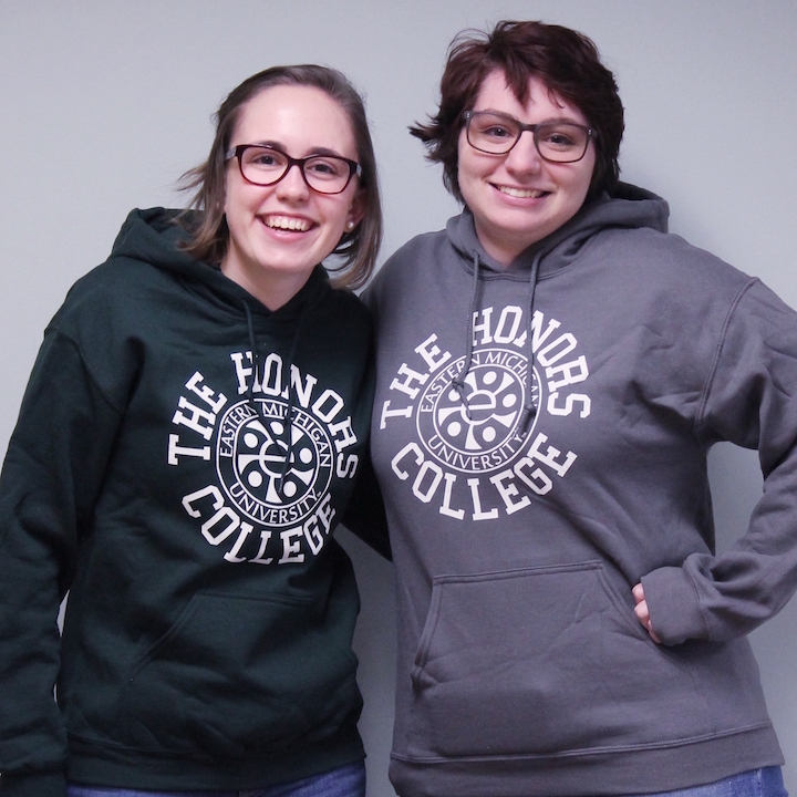 Two students standing together wearing gray hoodies.
