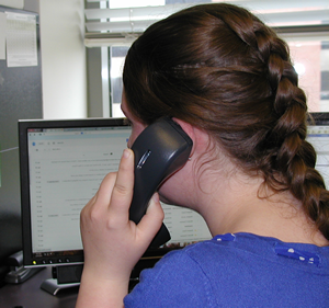 A photo of a female help desk employee on the phone with a customer.