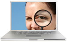 An image of a woman inside a computer screen looking back at the user through a magnifying glass.