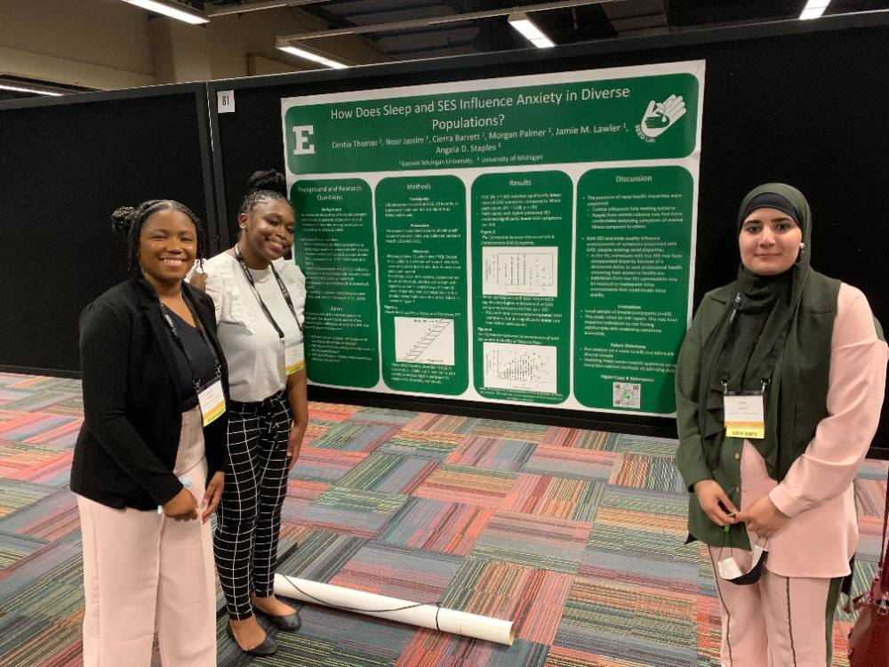 A photo of Centia Thomas and co-authors presenting a research poster.