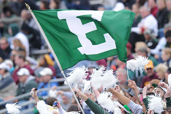 A photo of an EMU flag hoisted at a football game.