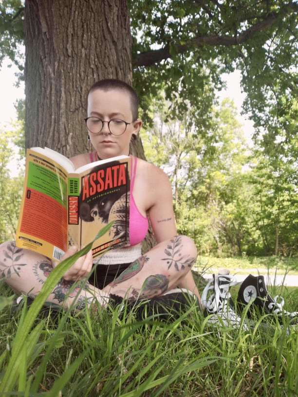tattooed person with shaved head reading