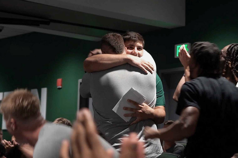 Dooley and Conti embrace while the team cheers