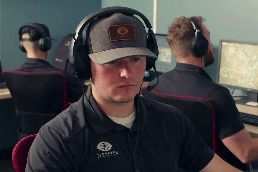 Man with ZeroEyes logo on hat and shirt in a control room